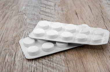 Tahta bir arka planda su toplayan bir pakette haplar. Masada iki kabarcık var..