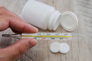 İlaç ve hapların arka planında termometre var. Yakın plan. Sağlık kavramı.