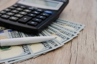 Dolar, tükenmez kalem ve hesap makinesi, ahşap arka planda. yakın plan.