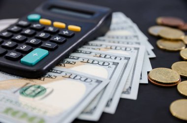 Siyah arka planda dolar, bozuk para ve hesap makinesi. İş konsepti...