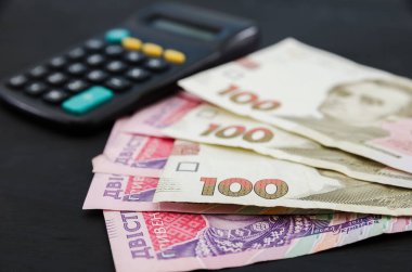 Siyah zemin üzerinde 100 ve 200 hryvnia ve hesap makinesi.