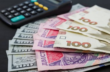 100, 200 hryvnias, dolar ve siyah arka planda bir hesap makinesi..