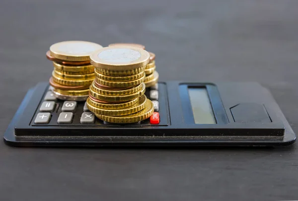 Pile Monete Una Calcolatrice Uno Sfondo Nero — Foto Stock