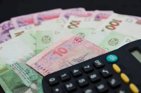 Siyah arkaplanda farklı hrivniyalar ve hesap makineleri. Bir sürü Ukrayna parası..