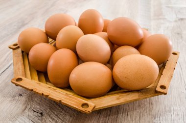 Tahta bir masada ahşap bir tabakta tavuk yumurtası. Yakın plan..