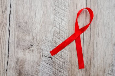 AIDS kavramı. Ahşap arka planda kırmızı kurdele.