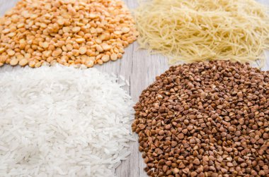 Tahta zemin üzerinde karabuğday, pirinç, bezelye ve makarna. Yakın plan. Çeşitli tahıl ve baklagiller.