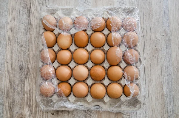 Kippeneieren Een Kartonnen Doos Plastic Omwikkeld Een Houten Tafel — Stockfoto