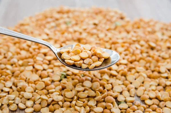 Bir kaşık içindeki bezelyeler bezelye homurdanmalarının arka planına karşı.