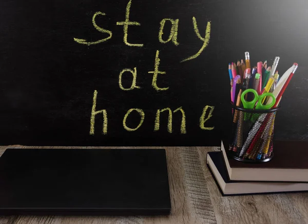 テーブルの上の学校用品やラップトップ 黒板の碑文は 家にいる 隔離の概念 コロナウイルス感染の拡大を防ぎます 距離学習の概念 — ストック写真