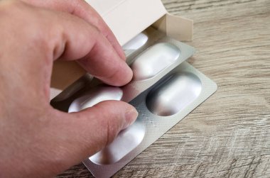 Bir el, kutudan çıkan haplarla su topladı. Yakın plan. Ahşap arkaplan.