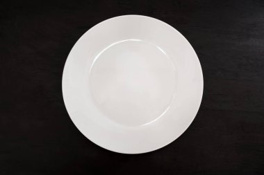 Siyah arka planda beyaz plaka var. Yukarıdan bak. Boş tabak.