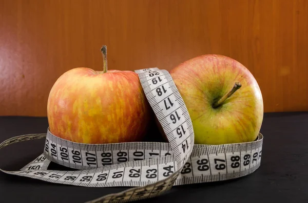 The concept of weight loss and diet. Two apples and a measuring tape on the table.