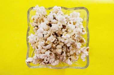 Sarı arka planda cam tabakta patlamış mısır. Yukarıdan görüntüle.