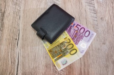 Ahşap bir arka planda 500, 200 Euro 'luk siyah bir erkek cüzdanı. Yukarıdan görüntüle.