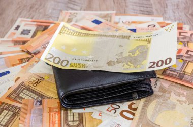 Avro banknotlarının arka planında 200 avro ve siyah bir adamın cüzdanı var. Çok para. Para arkaplanı.