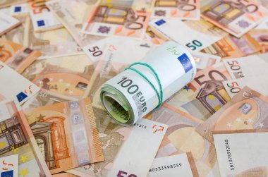 Para arka planda. Avro banknotlarının arka planında 100 avroluk bir rulo halinde yuvarlandı..