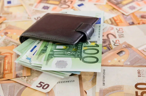 Avro banknotlarının arka planında siyah bir adamın cüzdanına 100 avro. Çok para..