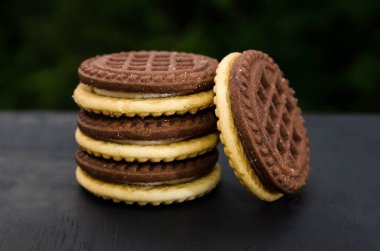 Siyah arka planda sandviç kurabiyeleri. Yakın plan. Lezzetli, kremalı çifte kurabiye..