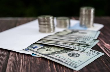 Tahta bir arka plandaki zarfta yığınla para ve dolar var. Tasarruf veya ekonomi kavramı