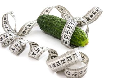 Beyaz arka planda salatalık ve mezura. Diyet kavramı.