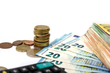 Hesap makinesi ve beyaz üzerine bozuk para olan bir sürü euro banknotu. Yakın plan..
