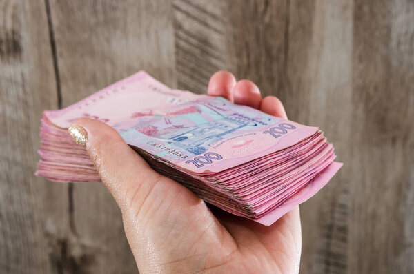 a lot of hryvnia in hand on a wooden background. Close-up.