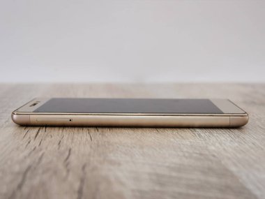 Ahşap bir arka planda akıllı telefon. Yan görünüm.