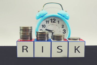 Riskli beyaz küpler, çalar saat ve yığınla bozuk para. Risk yönetimi kavramı.