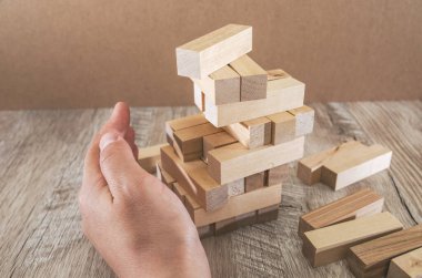 İş hayatında iş riskleri. Planlama gerektiren meditasyon, bir işte riski azaltmaya karar verirken dikkatli olmalıdır. El, kulenin düşmesini engellemeye çalışıyor..