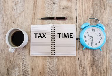 Vergi zamanı - Vergi beyannamesi, metin, model veya şablon için boş alanı olan iş yerinde vergi beyanı. Alarmlı saat ve bardak içeren bir not defterine bir yazı.