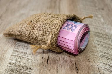 200 hryvnia, tahta bir arka planda küçük bir çuval içinde bir rulo içinde yuvarlandı..