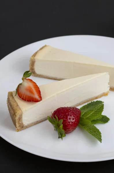 Çilekli cheesecake siyah arka planda bir tabakta