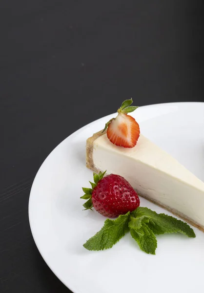 Çilekli cheesecake siyah arka planda bir tabakta