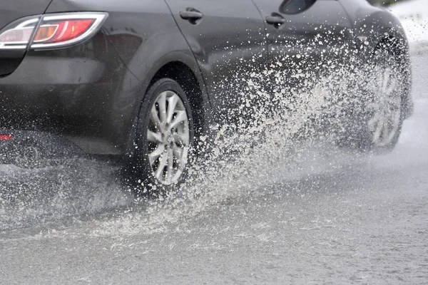 Salpicando agua de debajo de las ruedas del coche — Foto de Stock