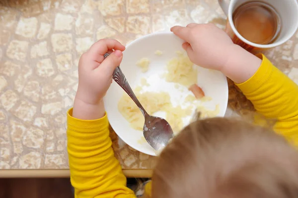 Una bambina mangia la sua cena a tavola — Foto Stock