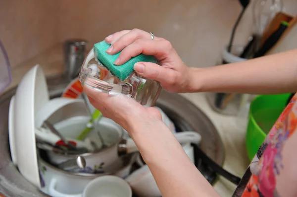 Female hands wash dishes at home in the sink