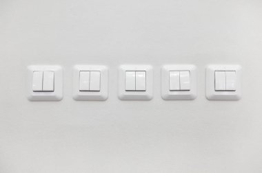 Beyaz duvarda bir sürü beyaz ışık düğmesi var.