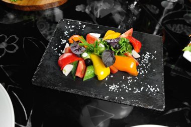 Restoranda tahta bir tahtanın üzerinde dilimlenmiş sebzeler, salatalıklar, domatesler, biberler, marul yaprakları.