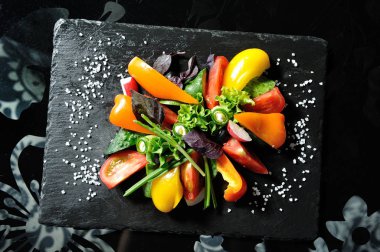 Restoranda tahta bir tahtanın üzerinde dilimlenmiş sebzeler, salatalıklar, domatesler, biberler, marul yaprakları.