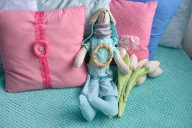 Yumuşak oyuncak tavşan yastıklarla yatakta yatıyor.