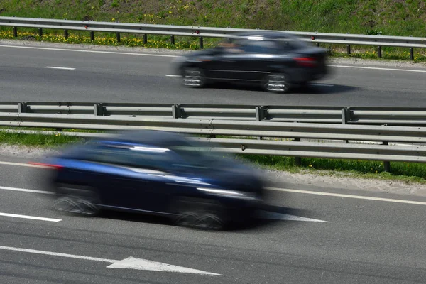Un coche azul a alta velocidad recorre el camino, borroso en movimiento — Foto de Stock