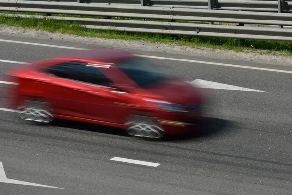 Un coche rojo a alta velocidad pasea por la carretera, borroso en movimiento — Foto de Stock