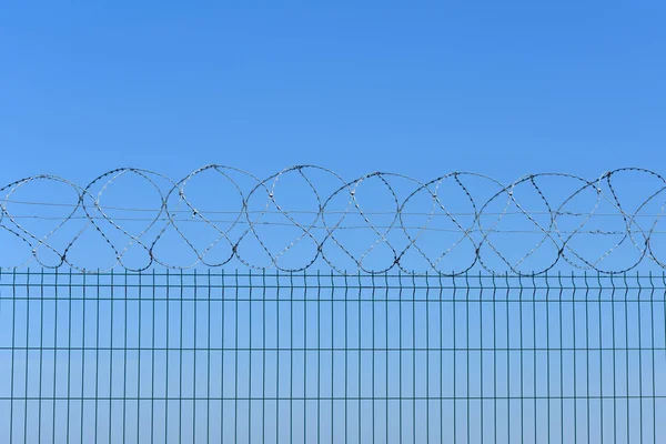 La cerca de alambre de púas en el fondo del cielo azul — Foto de Stock
