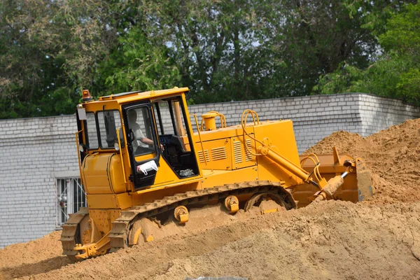 Um bulldozer rakes a areia para cima no armazém — Fotografia de Stock