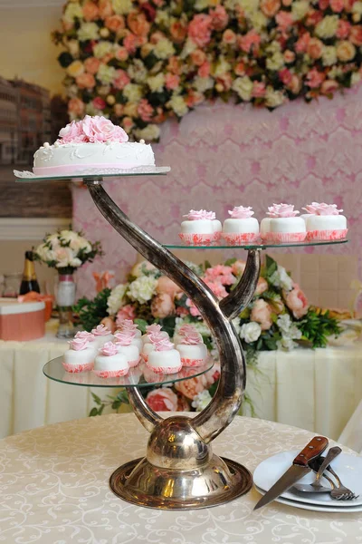 Wedding cake and cupcakes on a beautiful stand on the table