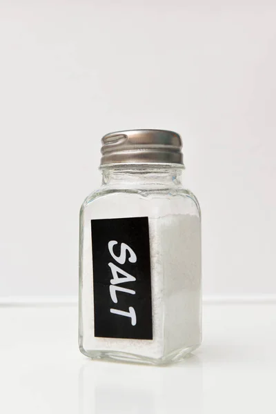 A small jar with salt on a white background, with an inscription — Stock Photo, Image