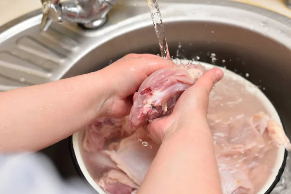 Frau wäscht Hühnerfleisch in der Spüle lizenzfreie Stockfotos