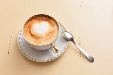 Bir fincan kahve ve antika bir masada kaşık.