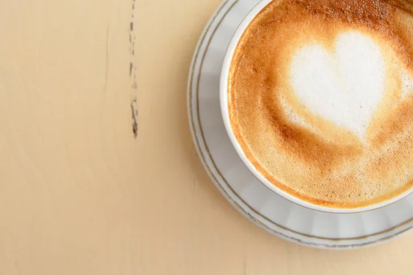 Uma xícara de café com um padrão de coração em uma mesa vintage — Fotografia de Stock